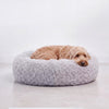 Cama para perro redonda de peluche gris con perro acurrucado durmiendo, vista lateral